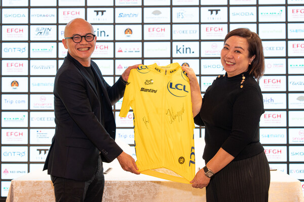 Dennis Ng, Executive Chairman of Embed Financial Group Holdings, and Agnes Goh, Managing Director of Evoke EXP, pose with a signed Yellow Jersey from champion cyclists Tadej Pogačar and Jonas Vingegaard. PHOTO: Evoke EXP