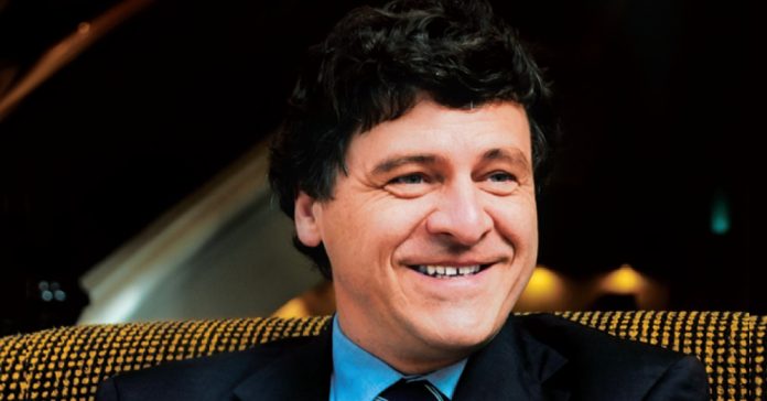 gerald wirth Gerald Wirth in a suit with necktie seated in a speckled yellow chair.