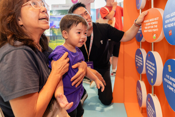 A family interacting with the “Stay in Control Flip Board” installation created by Tencent.